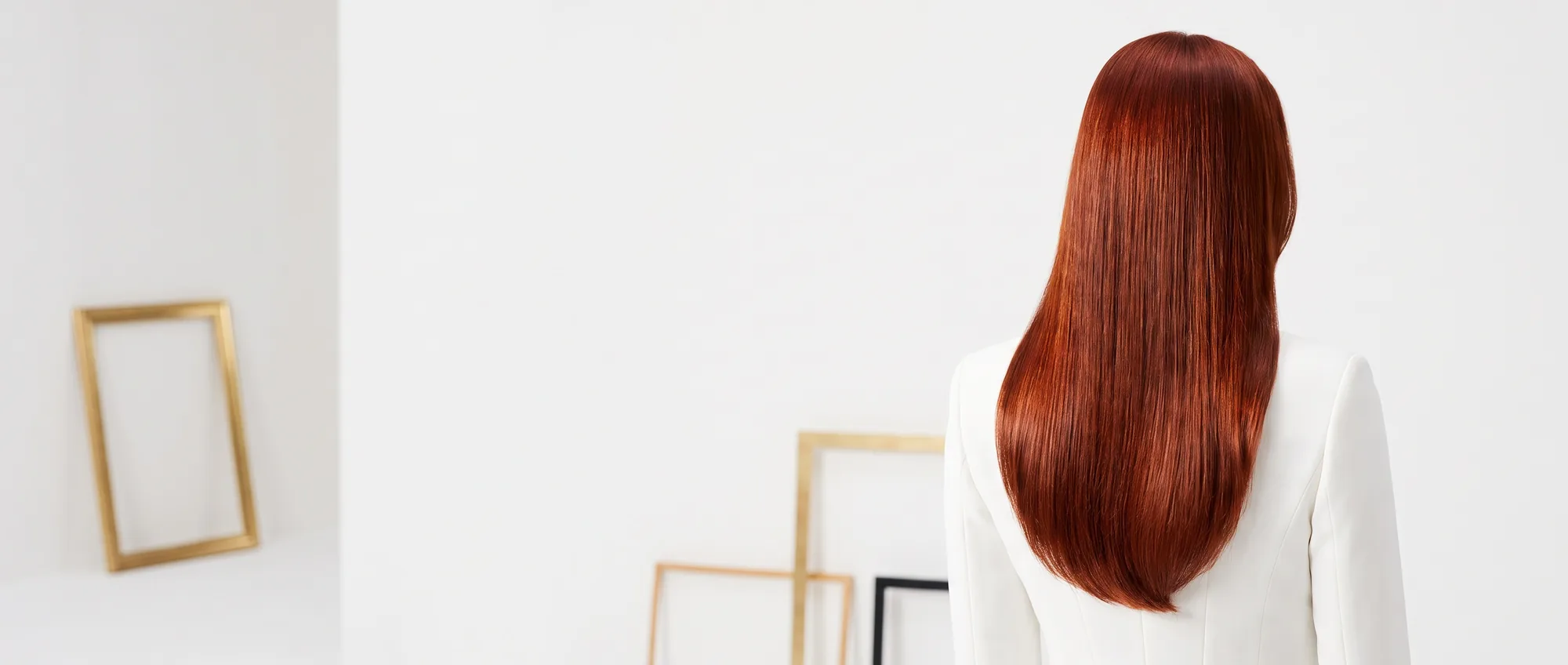 Una donna di spalle con lunghi capelli lisci tinti di rosso ramato intenso