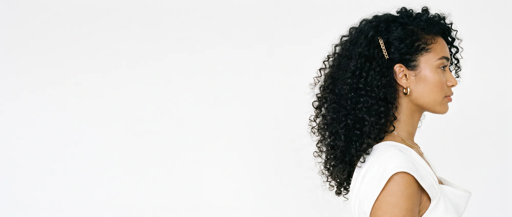 Profilo di una donna con capelli ricci scuri voluminosi e definiti, su sfondo bianco